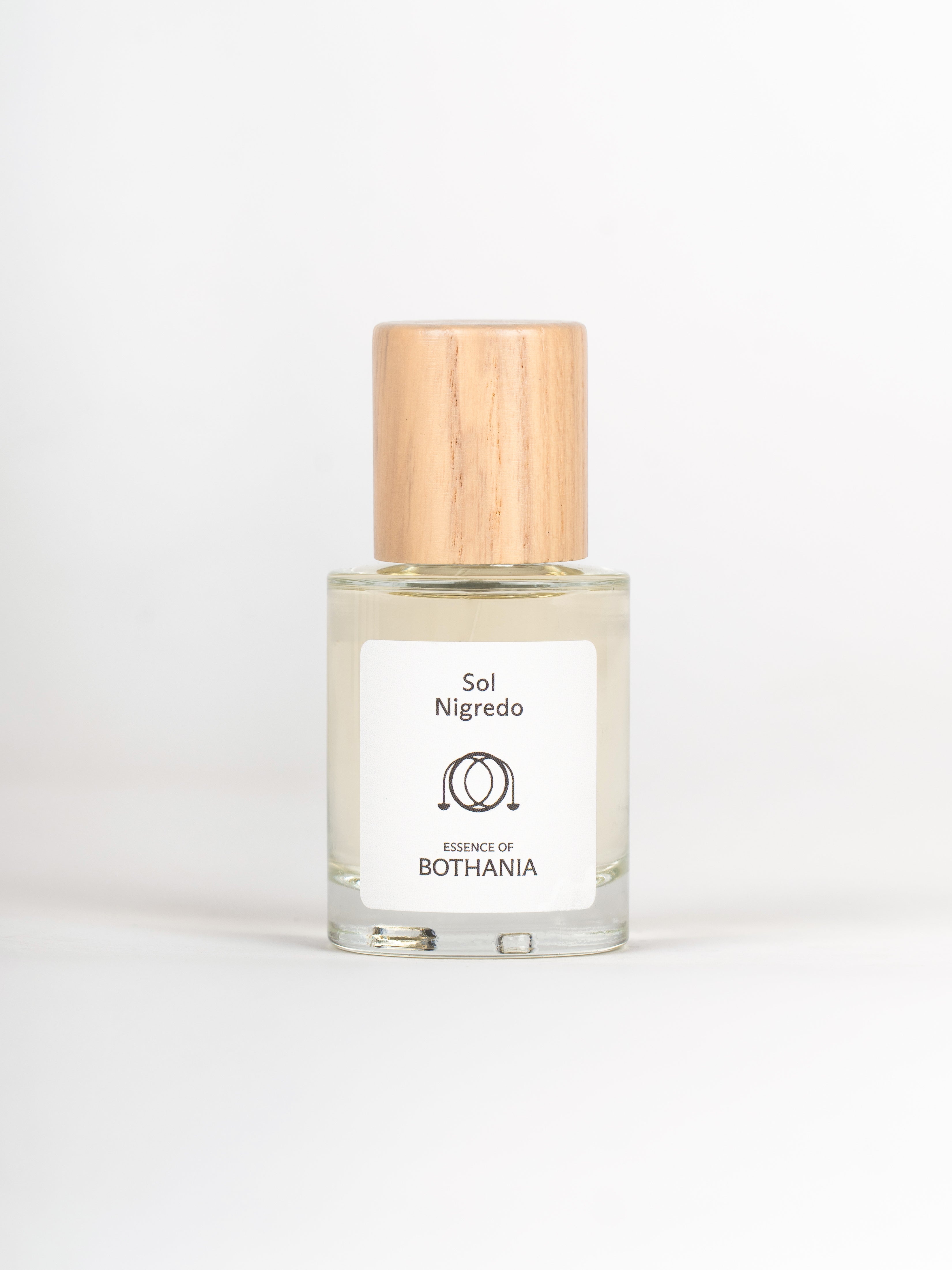 Clear glass bottle with wooden cap labeled 'Sol Nigredo' by 'Bothania' on a white background