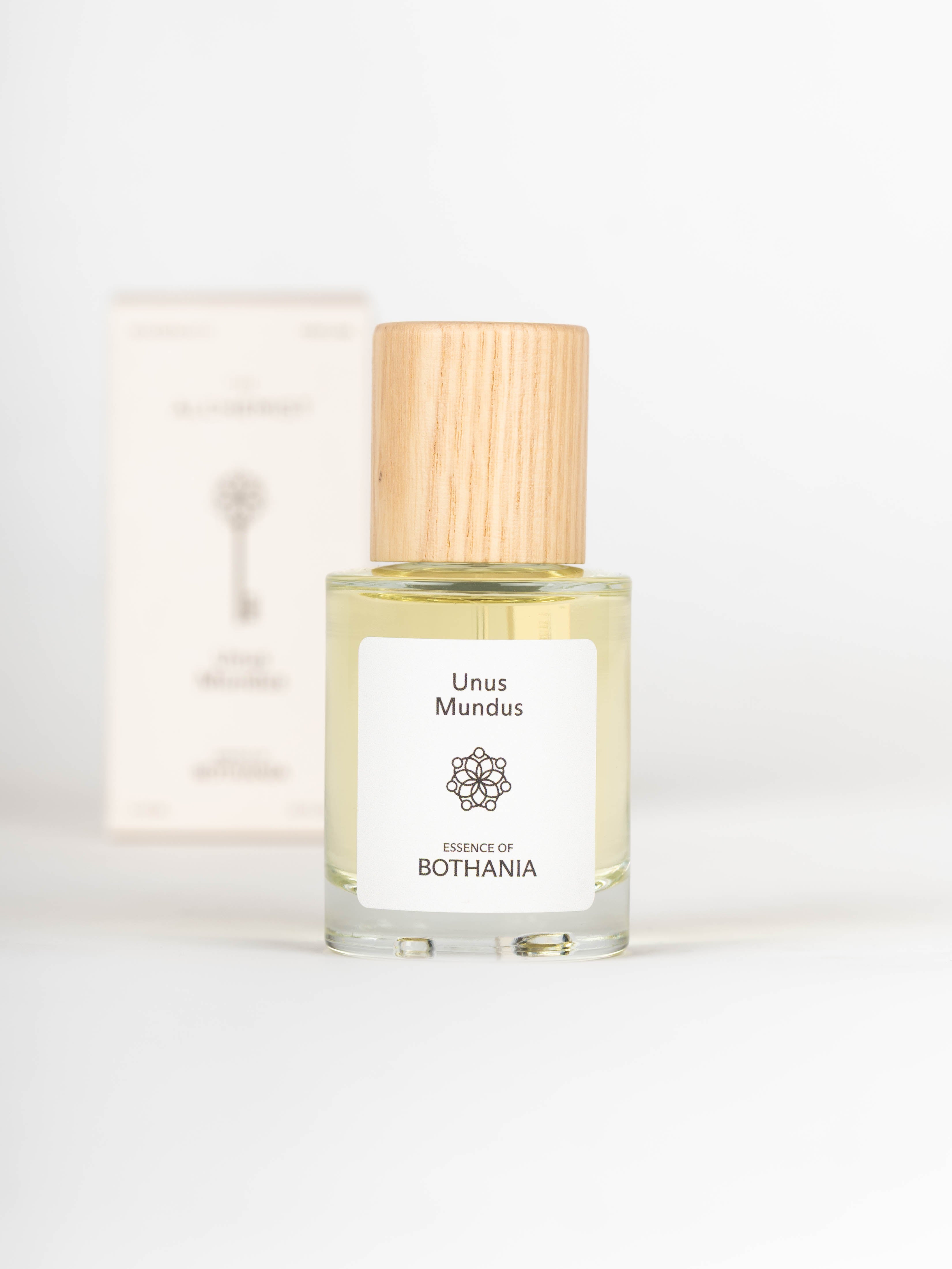 Unus Mundus perfume bottle with wooden cap on a white background with the packaging behind