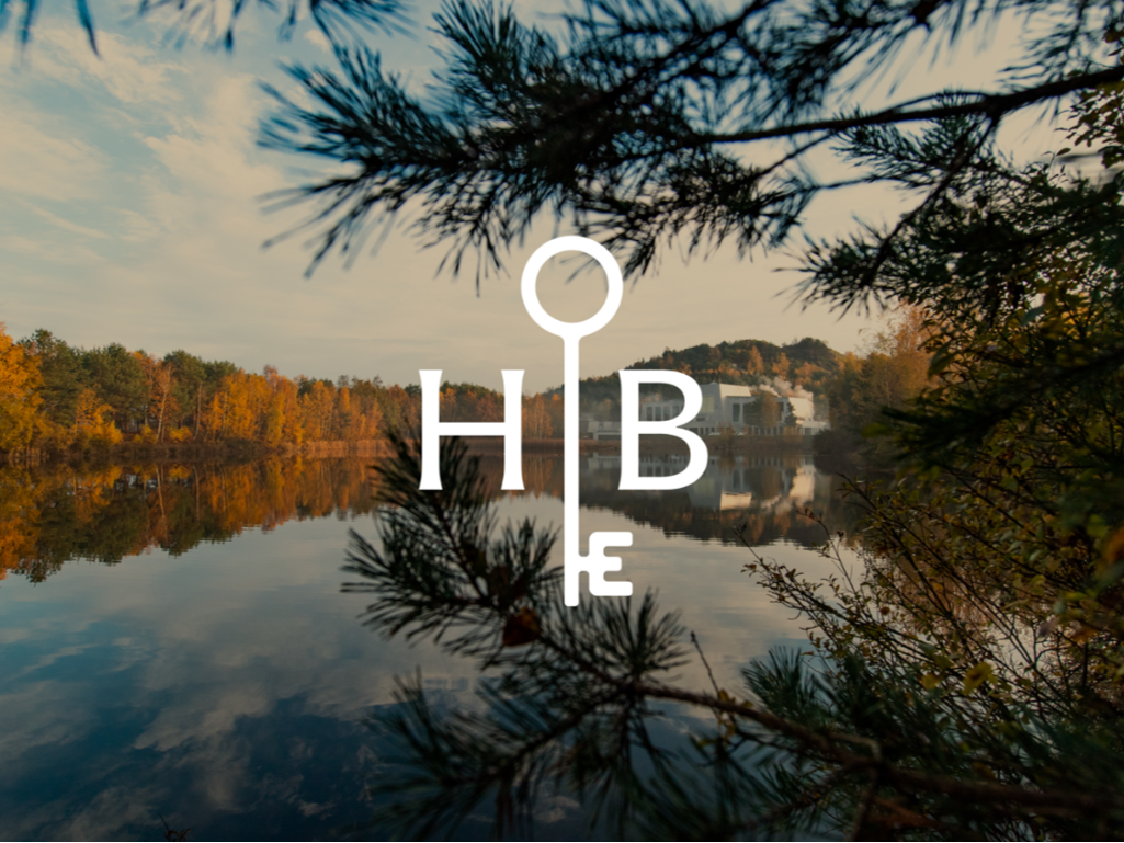 A serene lake scene with a tree branch in the foreground from Elaisa Wellness in Belgium, featuring the 'HOB' logo, representing House of Bothania.