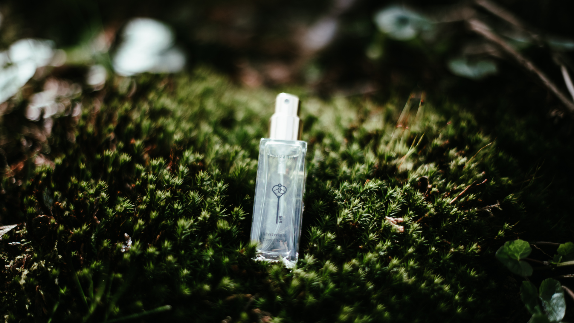Perfume bottle Mysterium Coniunctio made by House of Bothania placed in the moss in a deep green forest