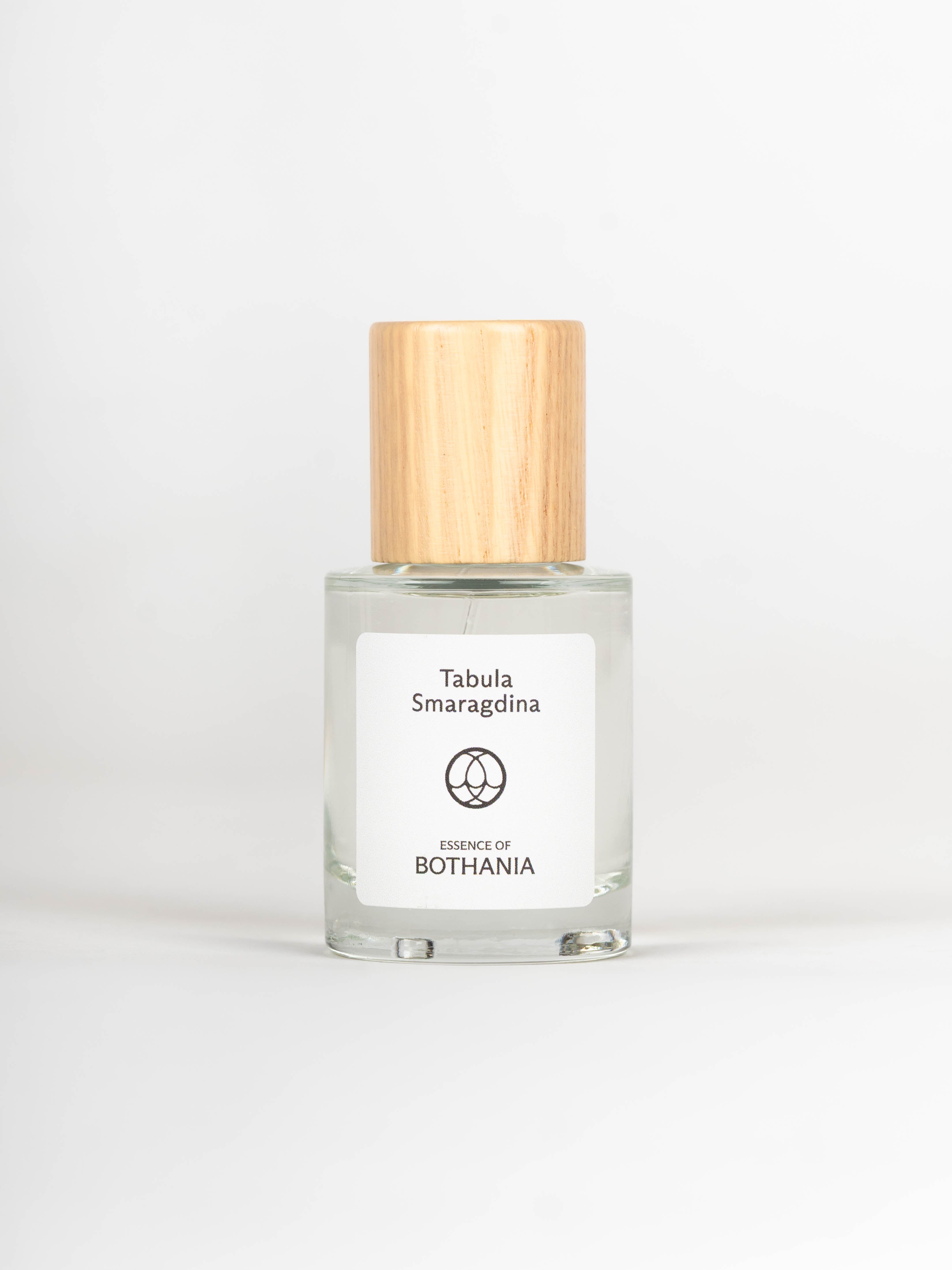 Clear glass bottle with wooden cap labeled 'Tabula Smaragdina' on a white background