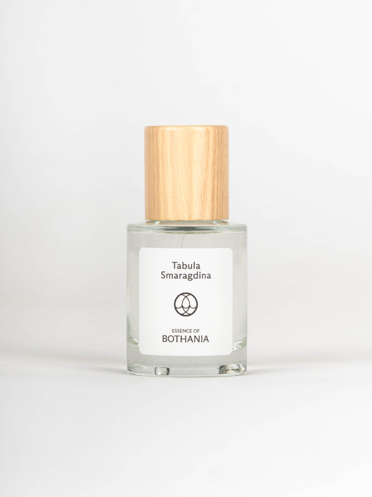 Clear glass bottle with wooden cap labeled 'Tabula Smaragdina' on a white background